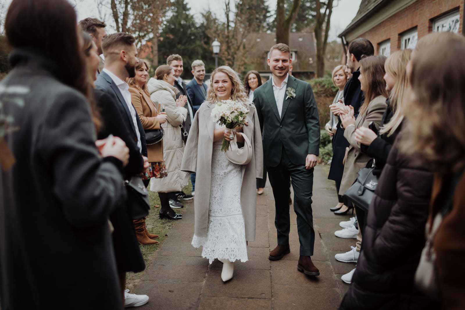 Alina und Hauke gehen Hand in Hand durch ein Spalier aus Gästen zum Eingang des Stavenhagenhauses