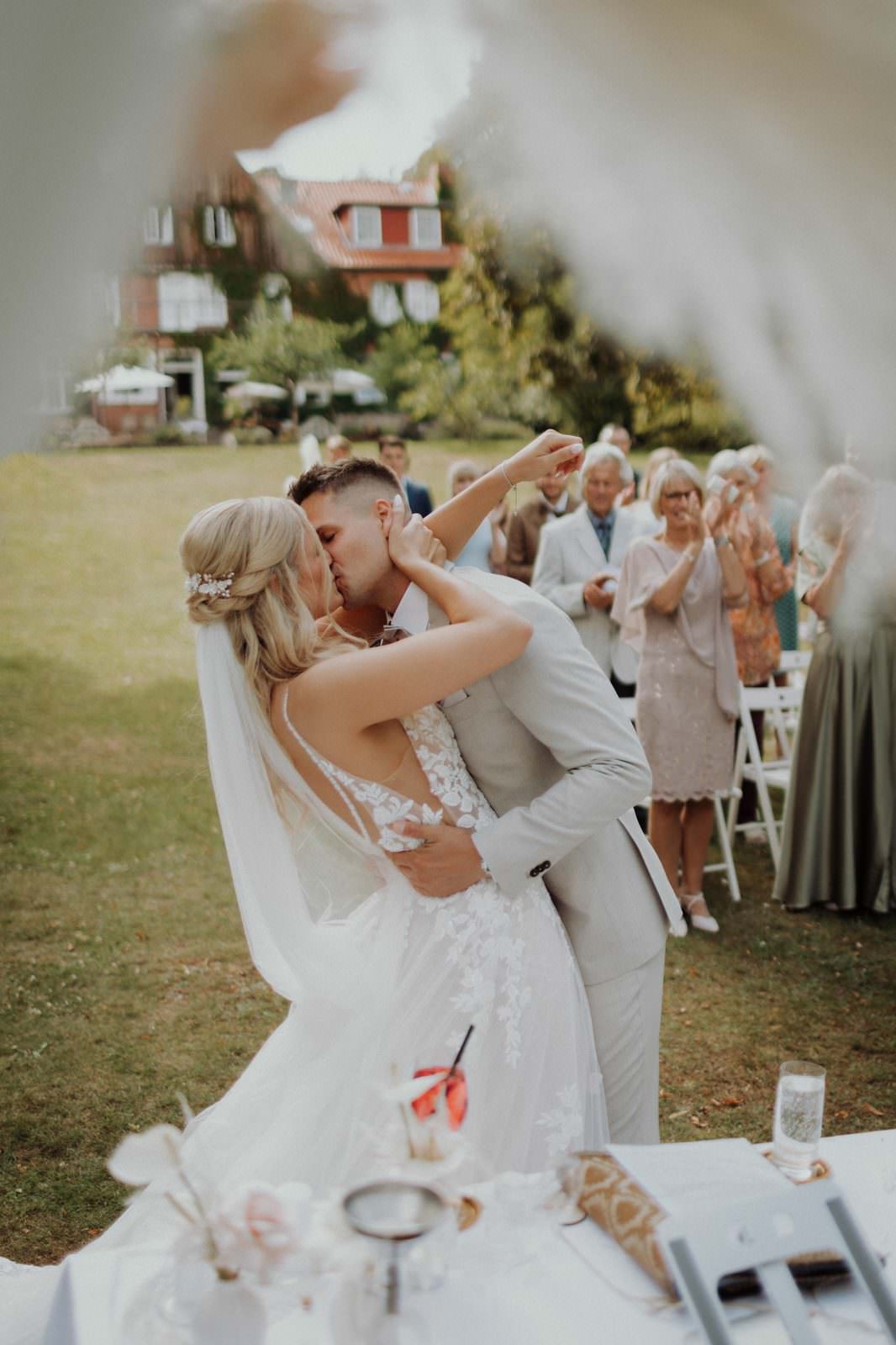 Hochzeitsfotograf Mölln — Cyana und Basti, Kuss beim Auszug Hotel Waldhof